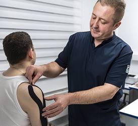 Врач мануальный терапевт, невролог, главный врач клиники Шуляков О.С. накладывает кинезиотейпы